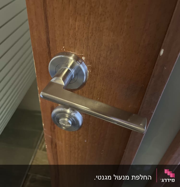 ידית דלת מתכתית על דלת עץ